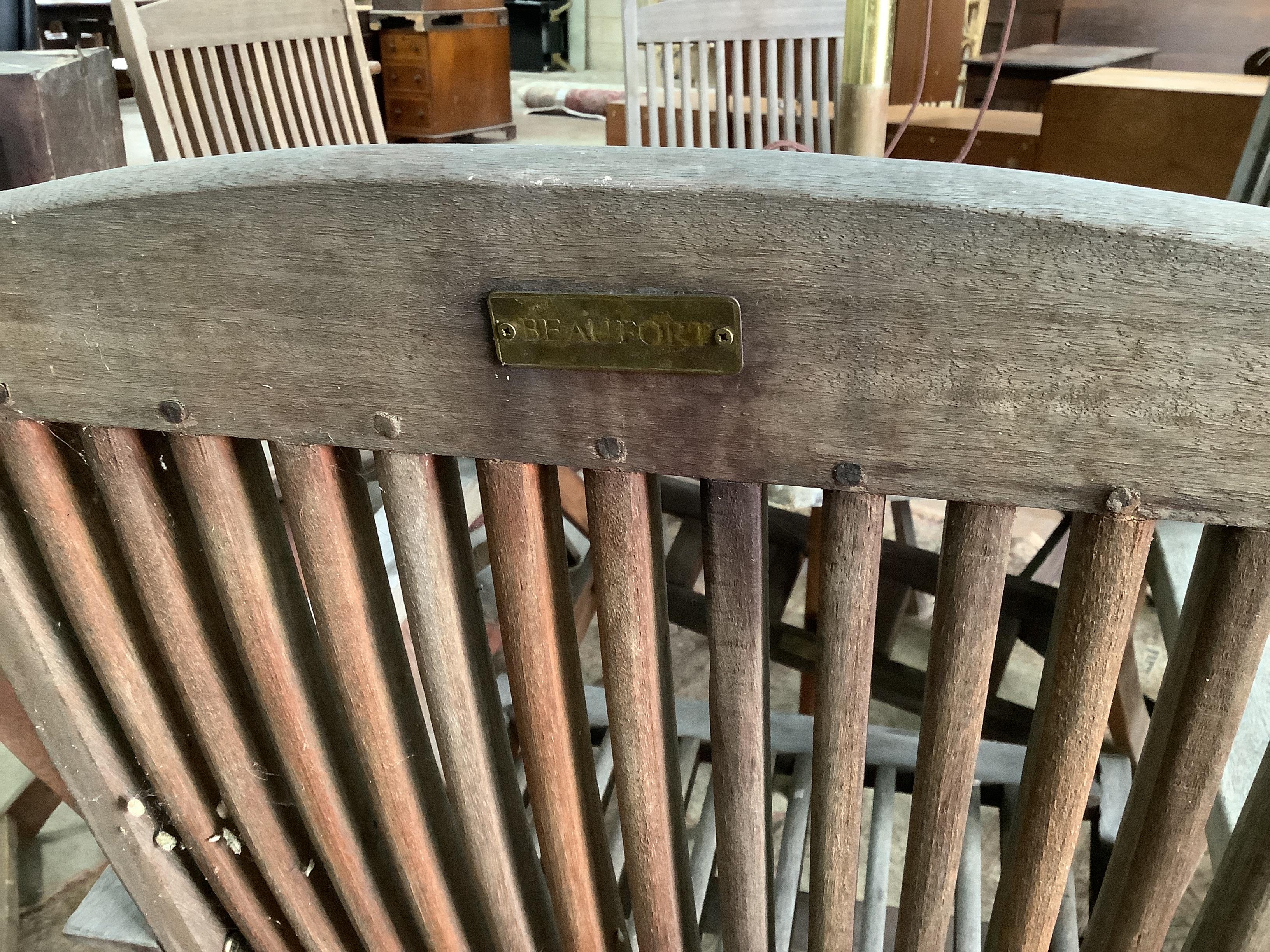 A weathered teak octagonal garden table, width 112cm, height 72cm together with six Beaufort weathered teak folding garden elbow chairs and green canvas crank parasol